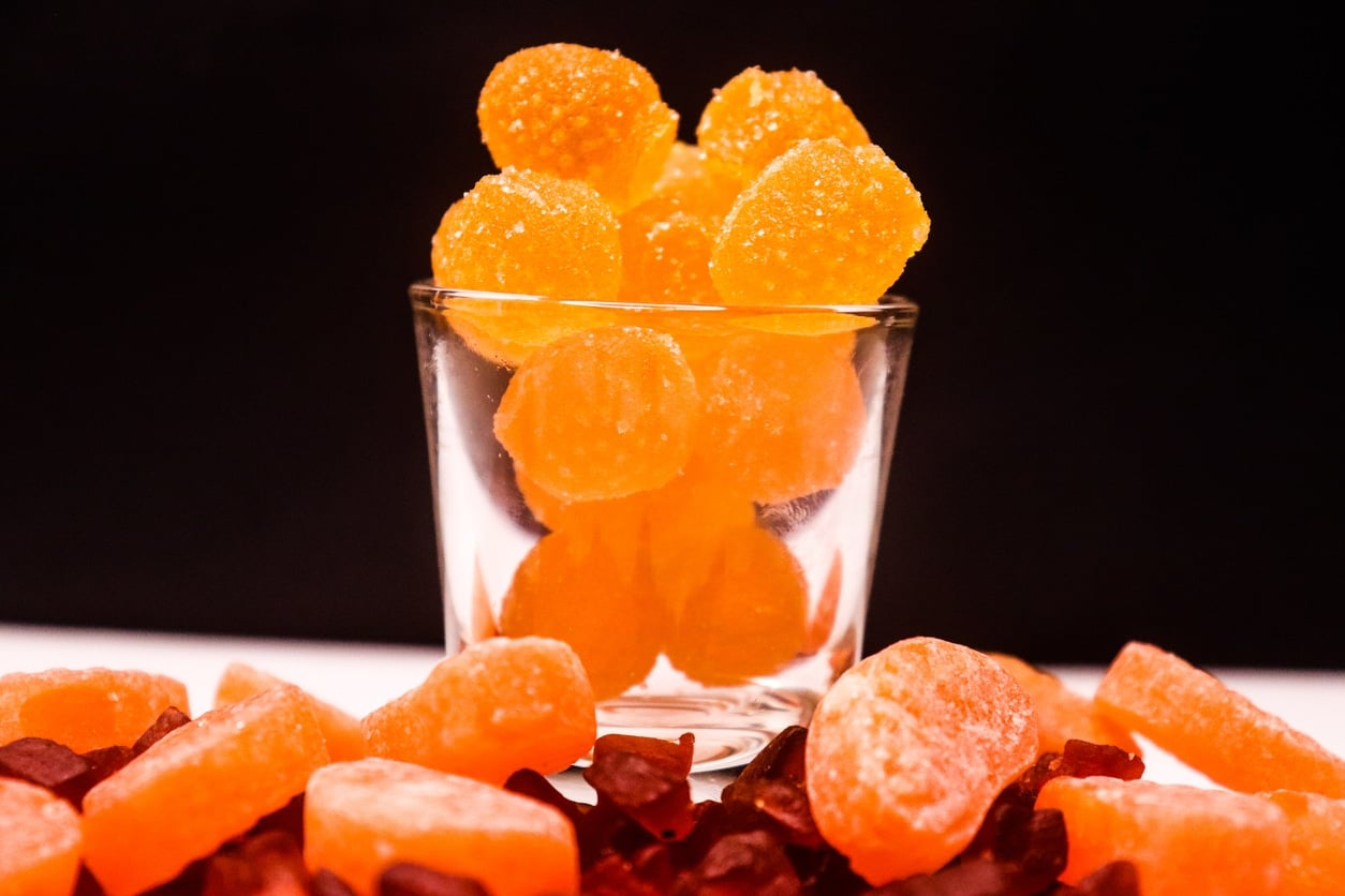 Orange flavored fruity tasty jelly and candy in transparent glass on black background.