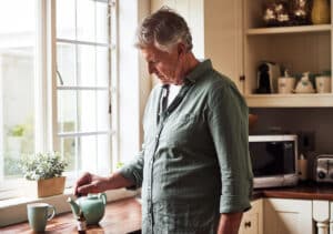 Senior man preparing a cup of tea with CBD oil inside of it at home during the day