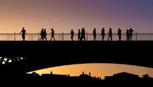 Silhouettes of people crossing the Triana bridge in Seville at sunset on a summer day